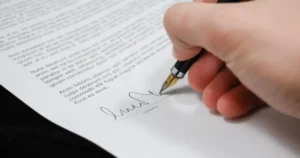 Mão assinando um documento representando a importância do planejamento sucessório na preservação do patrimônio