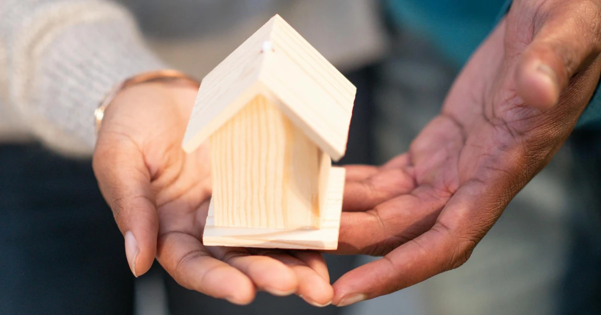 Casinha de madeira simples sendo segurada representando Usucapião