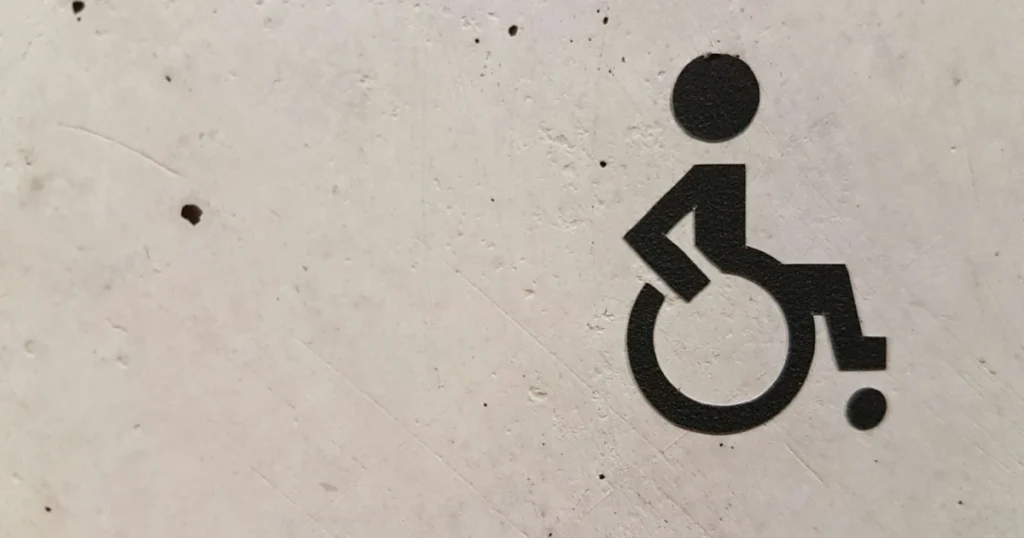 Símbolo de Acessibilidade pintado em uma parece para ilustrar o conteúdo sobre Benefícios previdenciários para pessoas com deficiência