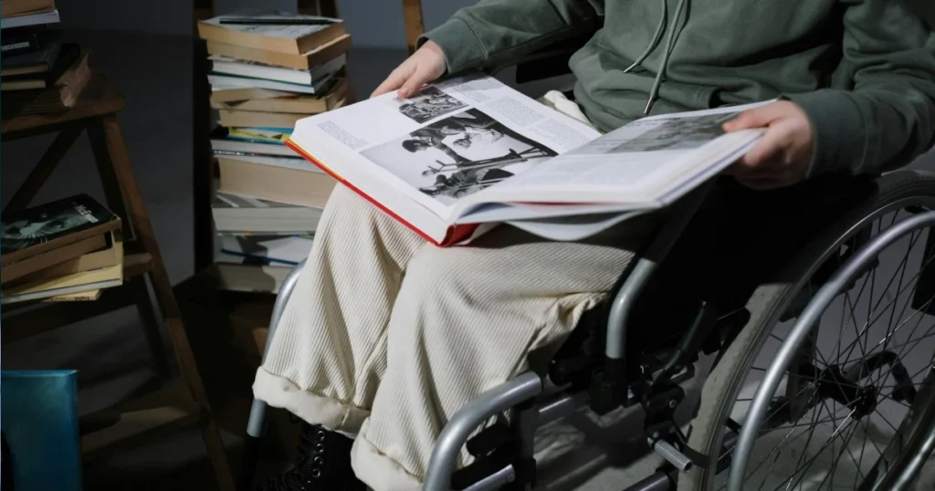 Homem sentado em uma cadeira de rodas lendo um livro representando a aposentadoria por invalidez