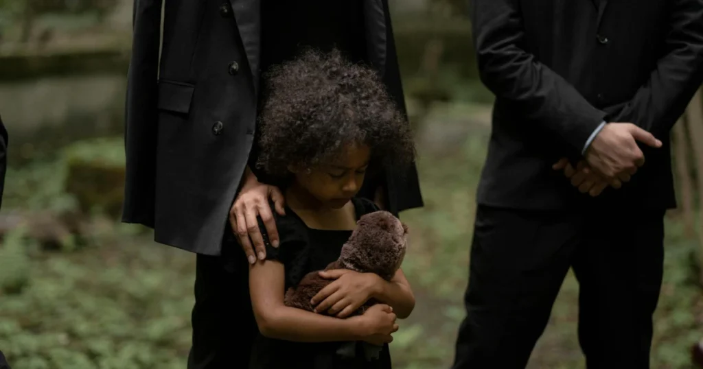 Garotinha triste segurando um urso de pelucia em um velório representando o tema pensão por morte