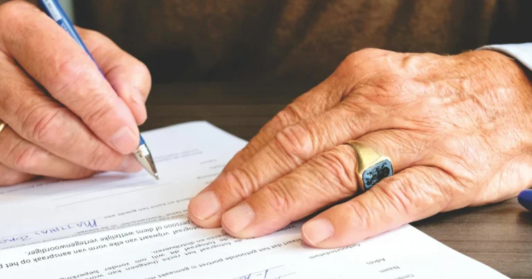 Mão assinando um documento ilustrando as cláusulas restritivas em testamentos